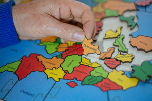 a partially made jigsaw puzzle of the counties of the British Isles, a hand is holding the piece of Oxfordshire.