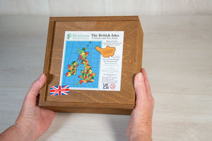 Two hand holding a stained wooden box, with a sliding lid. On the box is a label showing the Counties of the British Isles puzzle inside