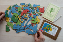 Load image into Gallery viewer, A pile of the pieces in the Countries of Europe Jigsaw Puzzle. Two hands hold pieces of the puzzle either side of the puzzle. 