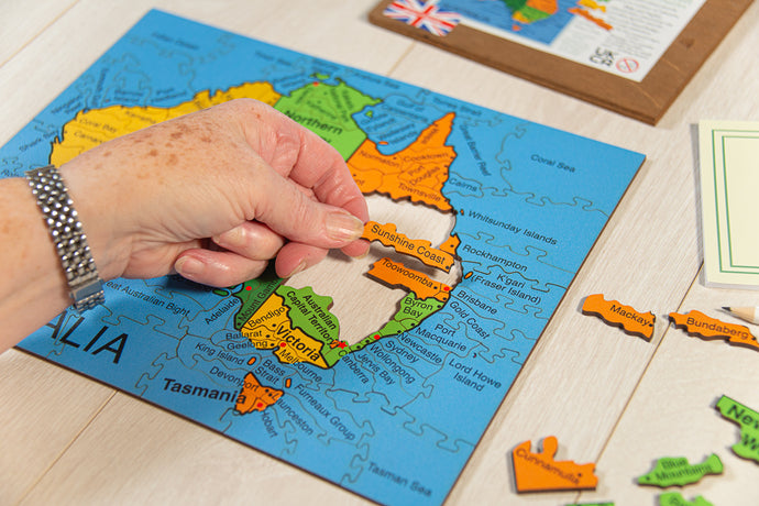 Map of Australia with wooden puzzle pieces on a wooden surface