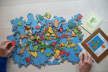 Load image into Gallery viewer, A pile of all the pieces of the Counties of the British Isles puzzle. There are two hands holding two pieces of the puzzle either side of the pile.